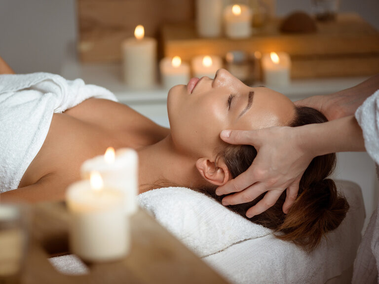 Eine Frau liegt entspannt auf einer Liege des Betula Spa mit Kerzen im Hintergrund.