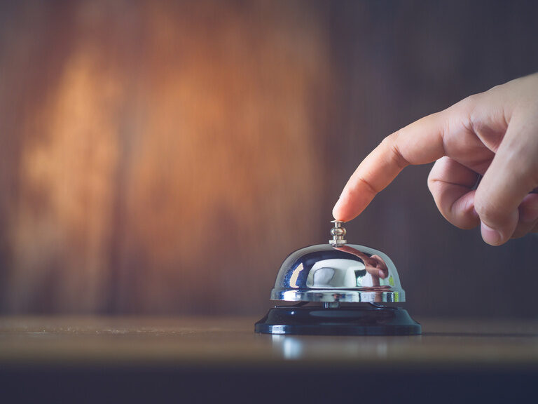 Am Empfangstisch des Hotels der Birkenhof in der Oberpfalz wird eine Klingel von einem Hotelgast gedrückt, um den Hotelservice zu erreichen.
